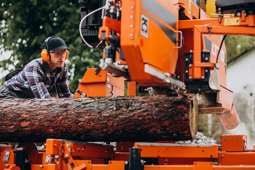 Mann arbeitet an einer elektrischen Holzmaschine zum Schneiden von Bäumen - Baumpflege